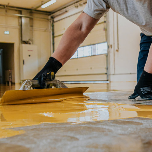 Worker applying epoxy to floor.