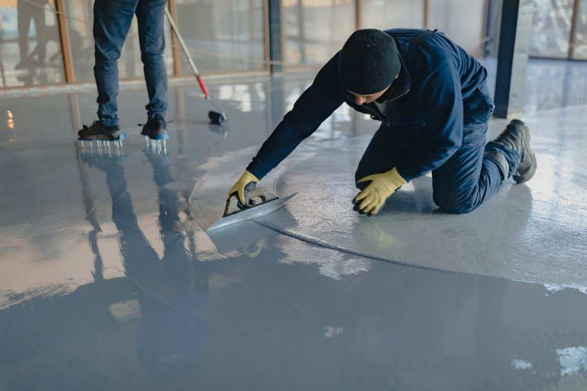 A worker applies gray epoxy resin to the new floor